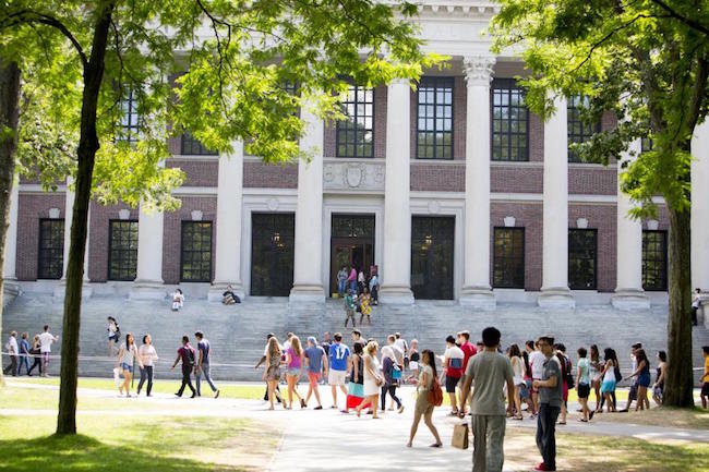 Students walking around in front of Harvard Business School's Harvard's Widener Library, decorated with columns.