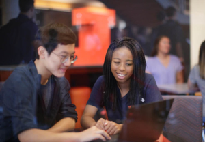 Two people in admissions and recruitment, smiling and reviewing an application on a laptop computer.