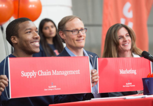 Gies students at Signing Day, smiling and holding up signs that read, "Supply Chain Management" and "Marketing."