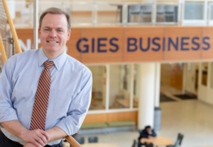 Jeffrey R Brown, Dean of Gies College of Business posing in front of Gies Business banner.